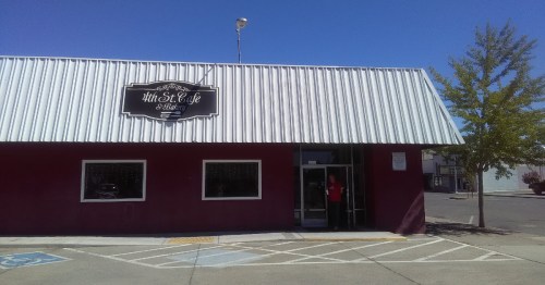 Exterior of 4th St. Café & Bakery, featuring a red facade, metal roof, and large windows on a sunny day.