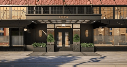 Exterior view of a Shinola store featuring a modern design, large windows, and potted plants at the entrance.