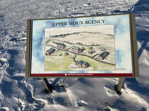 Sign depicting a historical illustration of the Upper Sioux Agency, set against a snowy landscape.