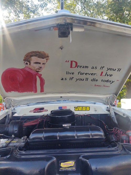 A car hood features a painting of a man with a quote: "Dream as if you'll live forever. Live as if you'll die today."