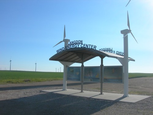 Sign for Langdon Wind Energy Center with wind turbines in the background under a clear blue sky.