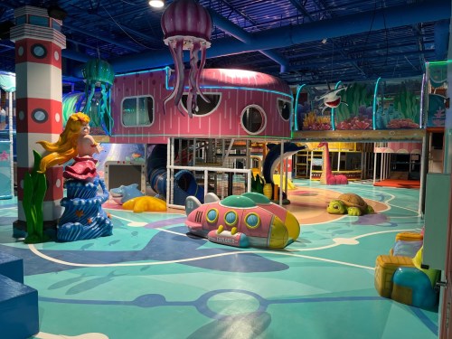 Colorful indoor play area featuring ocean-themed structures, including a submarine, jellyfish, and a turtle.