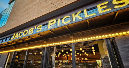 Exterior of Jacob's Pickles restaurant, featuring a bright sign and decorative lights.