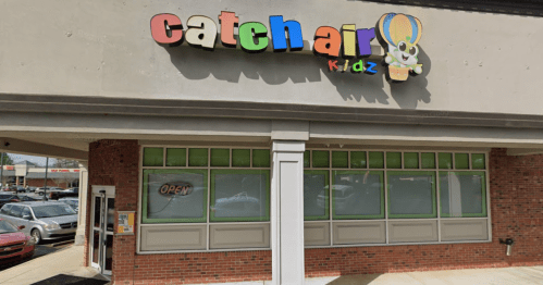 Colorful sign for "catchair kidz" on a storefront with large windows and an "Open" sign.