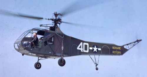 A vintage helicopter in flight, marked with "40" and a star insignia, with a pilot visible in the cockpit.