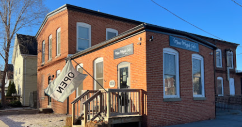 A brick building with a sign reading "New Magic Hall" and an open flag, set against a clear blue sky.