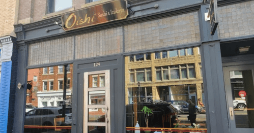 Exterior of Oish! Sushi Izakaya restaurant, featuring large glass windows and a stylish sign above the entrance.