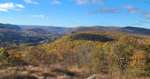 A scenic view of rolling hills covered in autumn foliage under a clear blue sky.