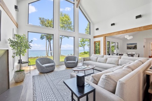 Bright, modern living room with large windows overlooking a scenic lake view, featuring a cozy sofa and stylish decor.