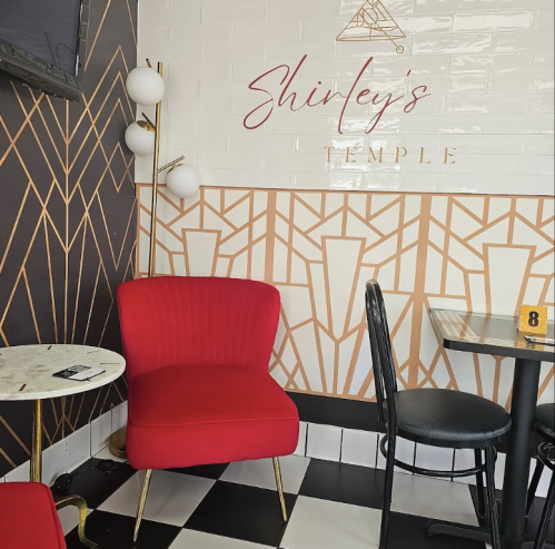 Cozy corner of a cafe featuring a red chair, marble table, and stylish geometric wall design.