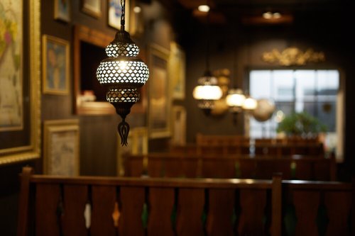 A dimly lit restaurant interior featuring decorative hanging lanterns and framed artwork on dark walls.