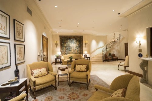Elegant lobby with plush seating, decorative artwork, and a grand staircase in a well-lit, upscale setting.