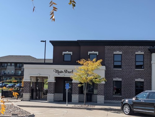 A building with a sign reading "Main Street," featuring a mix of brick and modern architecture under a clear blue sky.
