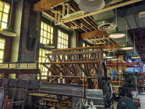 Interior of a historic industrial space featuring large machinery, wooden structures, and vintage lighting.