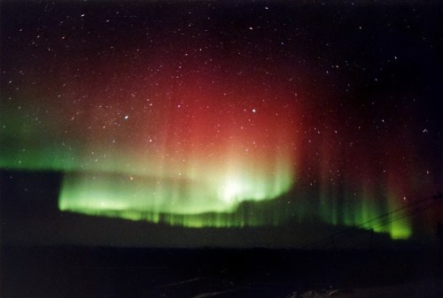 A stunning display of the aurora borealis with vibrant green and red lights against a starry night sky.