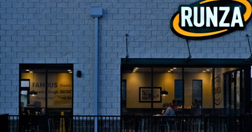 Evening shot of a modern Runza restaurant with interior seating visible through large windows.