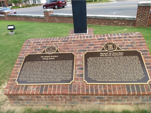 Plaques detailing the history of the Wright Brothers Flying School and Maxwell Air Force Base, set on a brick pedestal.