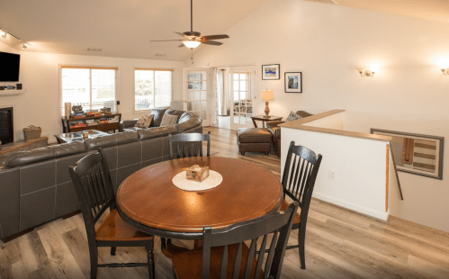 Cozy living space featuring a dining table, leather sofas, and large windows for natural light.