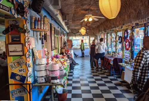 Colorful interior of a lively restaurant with checkered floors, decorations, and people enjoying the atmosphere.