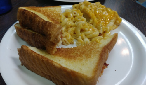 A plate with two slices of toasted bread and a serving of macaroni and cheese.