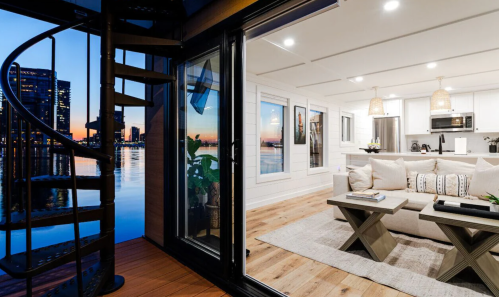 Cozy interior of a modern waterfront home with a spiral staircase and sunset views over the water.