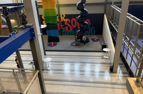 A colorful indoor play area with climbing walls, a slide, and people engaging in activities on the floor.