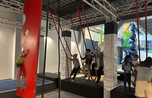 Children play on swings and climbing structures in a colorful indoor playground.