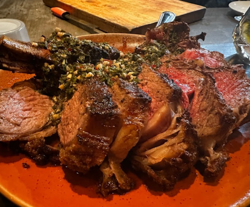 A large, juicy roast beef served on a plate, topped with a vibrant green herb sauce.