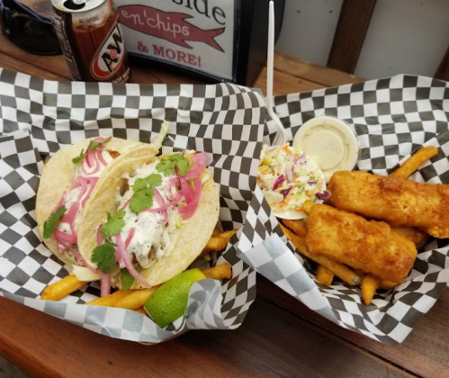 Two baskets of food: fish tacos with toppings, coleslaw, and crispy fish sticks served with fries.