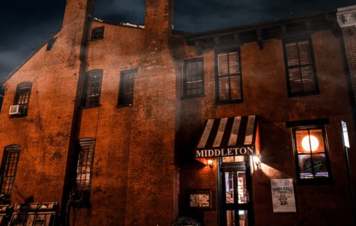 A historic brick building at night with a striped awning and the name "Middleton" illuminated above the entrance.