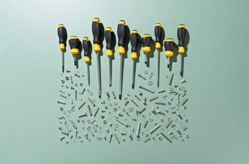 A collection of screwdrivers arranged above various screws, nuts, and bolts on a green background.
