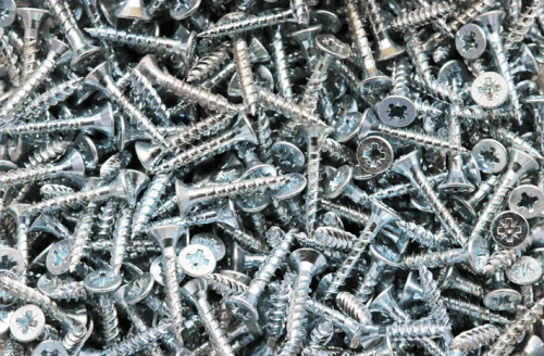 A close-up of a pile of shiny metal screws, featuring various sizes and types scattered together.