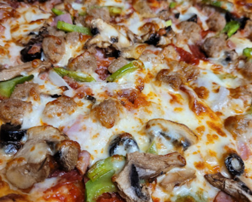 Close-up of a pizza topped with sausage, green peppers, mushrooms, olives, and melted cheese.