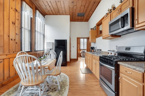 Bright kitchen with wooden walls, a dining table, and modern appliances, featuring a cozy, inviting atmosphere.