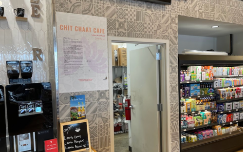 Interior of Chit Chaat Cafe showing a menu on the wall, an open door to the kitchen, and a display of snacks.