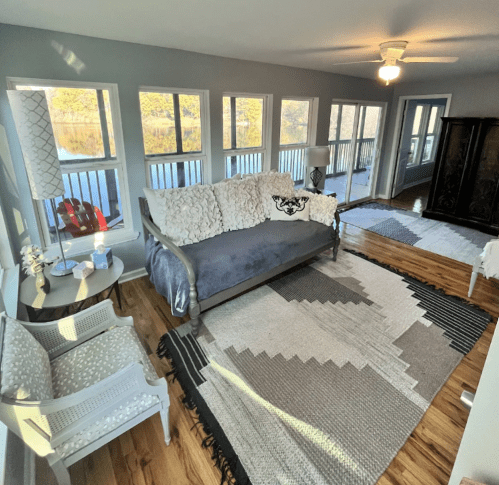 Cozy living room with a blue sofa, patterned rug, and large windows overlooking a scenic view.