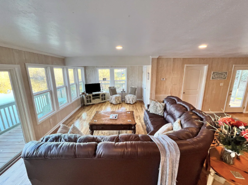 Cozy living room with a large brown sectional sofa, light wood floors, and windows offering natural light.
