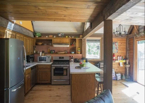 Cozy kitchen with wooden beams, modern appliances, and a central island, featuring warm, rustic decor.