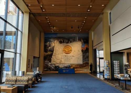 Interior of the Oregon Historical Society, featuring a large map mural and seating area.