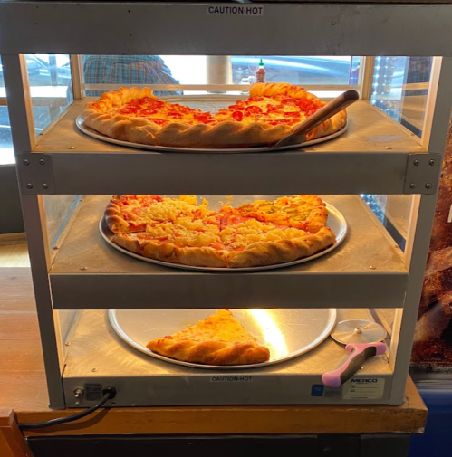 A display case with three trays of hot pizza, one slice removed from the bottom tray.