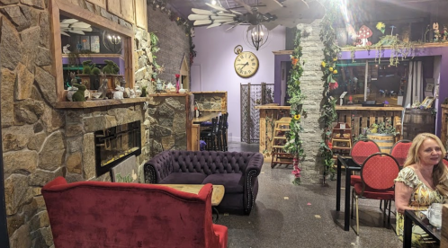 Cozy café interior with stone walls, plush seating, and decorative plants, featuring a warm, inviting atmosphere.