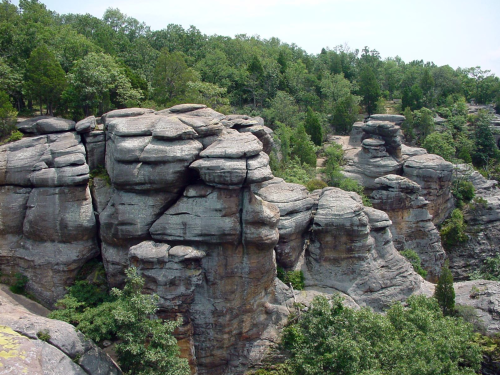 Rock formations surrounded by lush greenery under a clear sky.