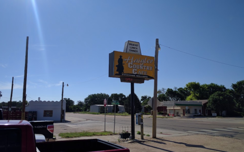 Sign for Haigler Country Cafe, with a clear blue sky and empty street in the background. Open for breakfast, lunch, and dinner.
