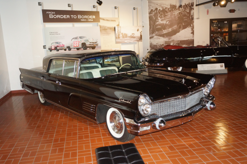 A classic black car displayed in a museum, showcasing vintage design and style from the mid-20th century.
