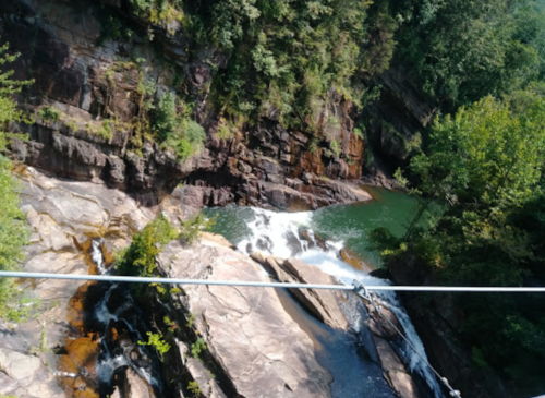 A scenic view of a waterfall cascading over rocky terrain, surrounded by lush greenery and trees.