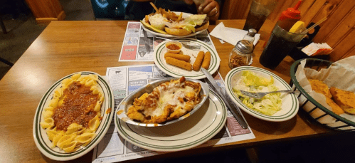 A table with various dishes: pasta, a baked dish, salad, and appetizers, set in a cozy restaurant.