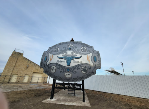 A large decorative sign featuring "Abilene, Kansas" with a bull design, set against a clear sky.