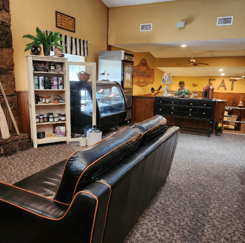 Cozy interior of a café featuring a black leather sofa, display case, and a counter with a staff member.