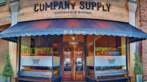 Exterior of a storefront labeled "Company Supply," featuring a canopy and large windows, located at 107 W. Jackson.