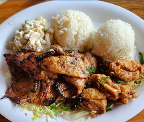 A plate of grilled chicken and pork, served with two rice portions and a side of creamy salad.